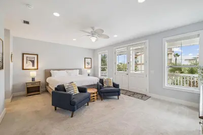 a bedroom with a bed and two blue chairs at Tram-on-Time Main House by 30A Escapes in Rosemary Beach
