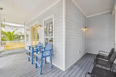 a porch with blue chairs on a house at Tram-on-Time Main House by 30A Escapes in Rosemary Beach