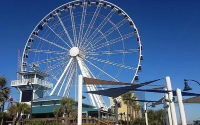 a large ferris wheel in front of a building at Perching Pretty at Sunbird in Panama City Beach