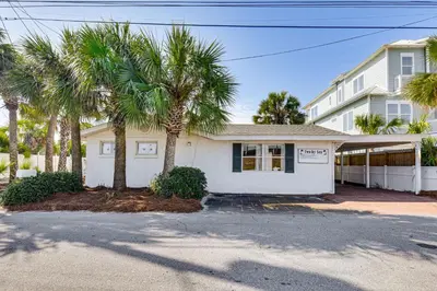 a white house with palm trees in front of it at Steps to Sand! PCB Haven with Furnished Outdoor Area in Panama City Beach