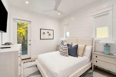a white bedroom with a bed and two windows at Pelayo Solage in Santa Rosa Beach
