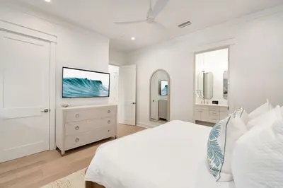 a white bedroom with a bed and a tv at Pelayo Solage in Santa Rosa Beach