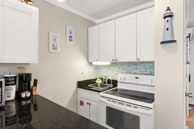 a kitchen with white cabinets and a white stove top oven at Beach Front Ocean View Condo - Top of the Gulf 105 in Panama City Beach