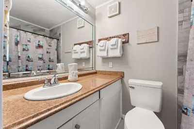 a bathroom with a sink and a toilet and a mirror at Beach Front Ocean View Condo - Top of the Gulf 105 in Panama City Beach