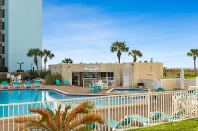 a swimming pool with chairs and a building at Beach Front Ocean View Condo - Top of the Gulf 105 in Panama City Beach