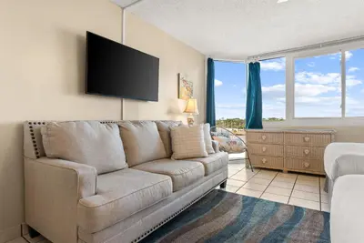 a living room with a couch and a flat screen tv at Beach Front Ocean Front Condo Top of the Gulf 516 in Panama City Beach