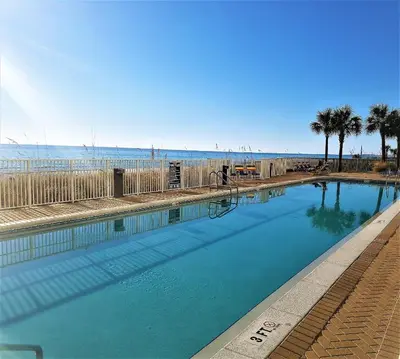 a swimming pool next to the beach with palm trees at Sugar Sand at Ocean Reef in Panama City Beach