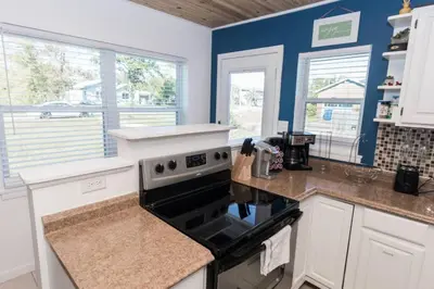a kitchen with white cabinets and a stove top oven at Pet Friendly Cheerful home on Emerald Coast - by SharpCat in Panama City