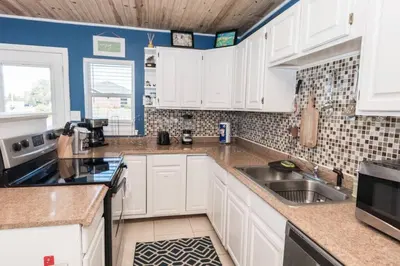 a kitchen with white cabinets and a sink at Pet Friendly Cheerful home on Emerald Coast - by SharpCat in Panama City