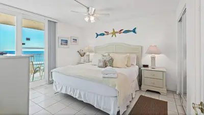 a bedroom with a bed and a balcony with the ocean at BeachCrest 1202 in Santa Rosa Beach