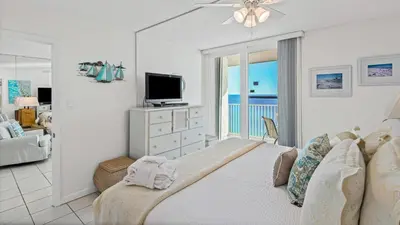 a bedroom with a bed with a television and a balcony at BeachCrest 1202 in Santa Rosa Beach
