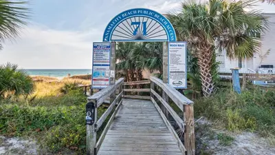 a boardwalk leading to a sign at the beach at Portside Resort V4 in Panama City Beach