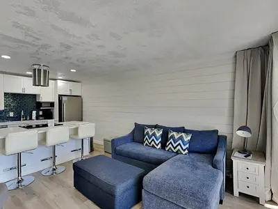 a living room with a blue couch and a kitchen at Edgewater Villa #105 in Panama City Beach