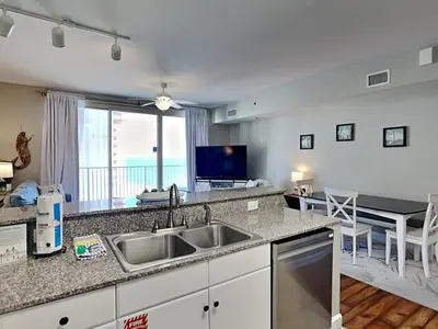 a kitchen with a sink and a living room at Shores of Panama #1707 in Panama City Beach