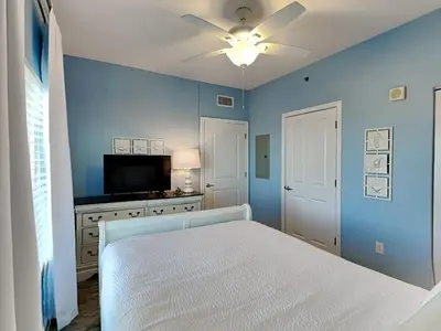a blue bedroom with a bed and a flat screen tv at Shores of Panama #1707 in Panama City Beach