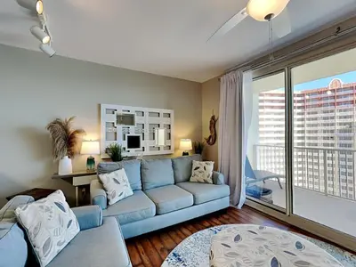 a living room with a blue couch and a large window at Shores of Panama #1707 in Panama City Beach