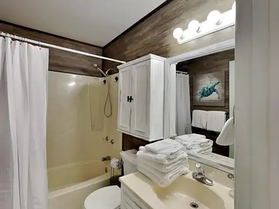 a bathroom with a sink and a toilet and a mirror at Stay Salty in Panama City Beach