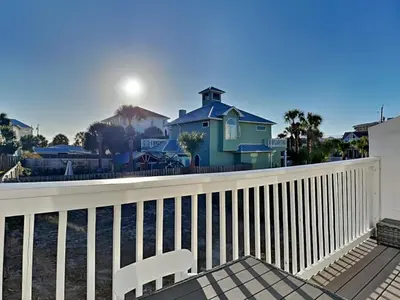a white chair on a balcony with a blue house at Stay Salty in Panama City Beach