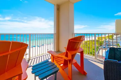 a balcony with a chair and a view of the ocean at The Sandy Pearl at Ocean Reef in Panama City Beach