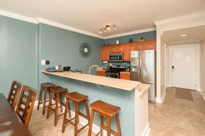 a kitchen with wooden cabinets and a counter with bar stools at Blue Horizon at Ocean Reef in Panama City Beach
