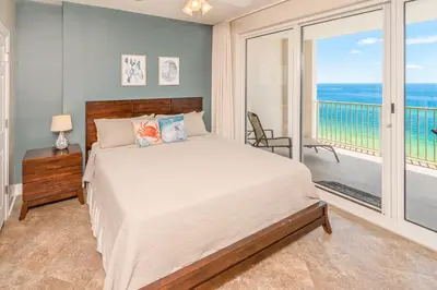 a bedroom with a bed and a balcony with the ocean at Blue Horizon at Ocean Reef in Panama City Beach