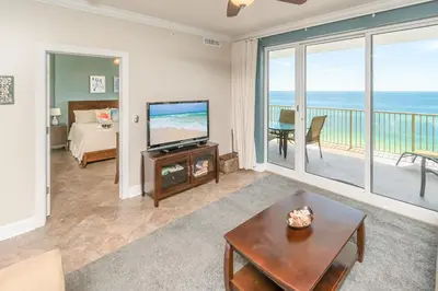 a living room with a bed and a television and a balcony at Blue Horizon at Ocean Reef in Panama City Beach