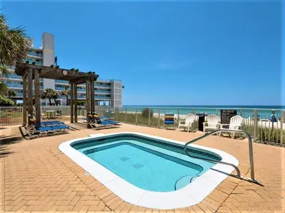 a swimming pool with a table and chairs and the beach at Forever Fun at Ocean Reef in Panama City Beach