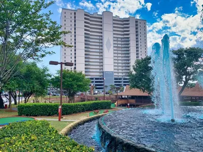a fountain in a park in front of a tall building at Forever Fun at Ocean Reef in Panama City Beach
