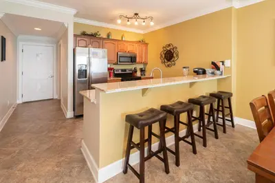 a kitchen with yellow walls and a counter with bar stools at Forever Fun at Ocean Reef in Panama City Beach