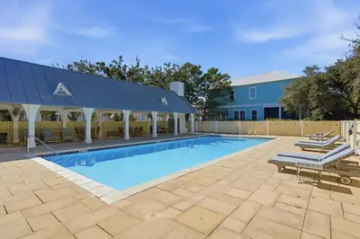 a swimming pool with chairs and a building at Family Coastal Escape in Inlet Beach