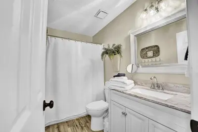 a bathroom with a sink and a toilet and a mirror at The Shell House in Panama City Beach