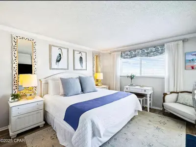 a bedroom with a bed and a chair and a window at Our Sea Side in Panama City Beach