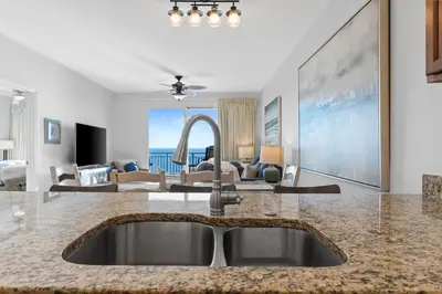a kitchen with a sink and a living room at Gulf-View Condo with Pool, Grill, Gym & Beachfront Resort Perks! in Panama City Beach