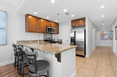 a kitchen with a counter and stools in a room at Gulf-View Condo with Pool, Grill, Gym & Beachfront Resort Perks! in Panama City Beach