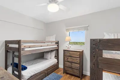 a bedroom with two bunk beds and a dresser at Gulf-View Condo with Pool, Grill, Gym & Beachfront Resort Perks! in Panama City Beach