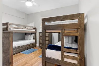 two bunk beds in a room with wooden floors at Gulf-View Condo with Pool, Grill, Gym & Beachfront Resort Perks! in Panama City Beach