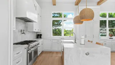 a white kitchen with a sink and a stove at Spacious Coastal Retreat Near Inlet Beach with Bikes Balconies Modern Design Bluewater View by Avantstay in Inlet Beach