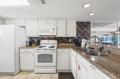 a kitchen with white cabinets and a stove and a sink at Commodore 0806 in Panama City Beach