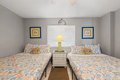 a bedroom with two beds and a lamp on a night stand at Commodore 0806 in Panama City Beach