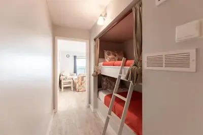 a small bedroom with a bunk bed and a ladder at The Summit 618 - Bright Waterfront Condo in Panama City Beach