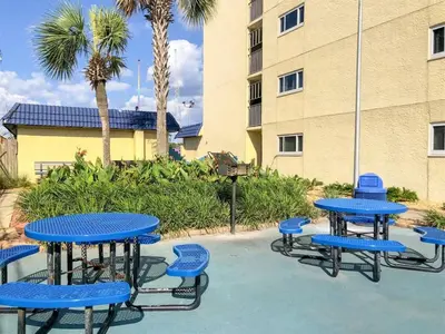 a group of blue tables and chairs in front of a building at The Summit 618 - Bright Waterfront Condo in Panama City Beach
