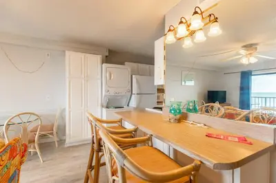 a kitchen with a table and chairs and a refrigerator at The Summit 618 - Bright Waterfront Condo in Panama City Beach