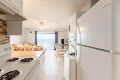 a kitchen with a refrigerator and a living room at The Summit 618 - Bright Waterfront Condo in Panama City Beach