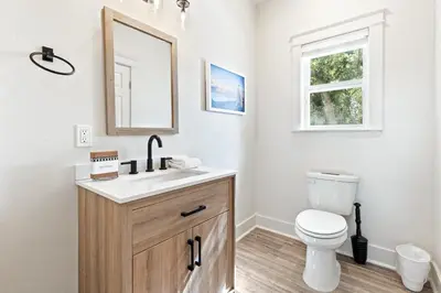 a bathroom with a toilet and a sink and a mirror at Our Seaside 4 BR Seagrove, HEATED Pool, bikes and 5 min to the beach in Santa Rosa Beach