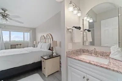 a bedroom with a bed and a sink and a mirror at The Summit 529 - Newly Remolded Beachfront Condo in Panama City Beach