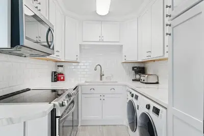 a white kitchen with white cabinets and a dishwasher at The Summit 529 - Newly Remolded Beachfront Condo in Panama City Beach