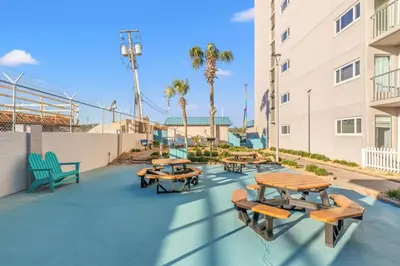 a patio with tables and benches and palm trees at The Summit 524 in Panama City Beach