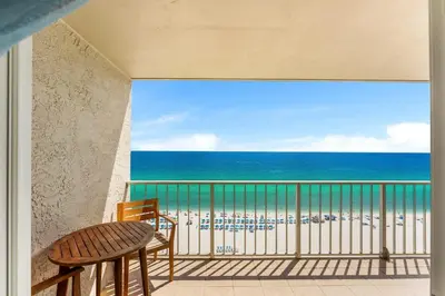 a balcony with a table and chairs and the beach at The Summit 1502 - Family Getaway & Beach Chairs in Panama City Beach