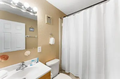 a bathroom with a toilet and a sink and a mirror at The Summit 1502 - Family Getaway & Beach Chairs in Panama City Beach