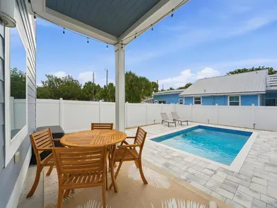 a patio with a table and chairs and a swimming pool at Horizon Dreams A in Panama City Beach
